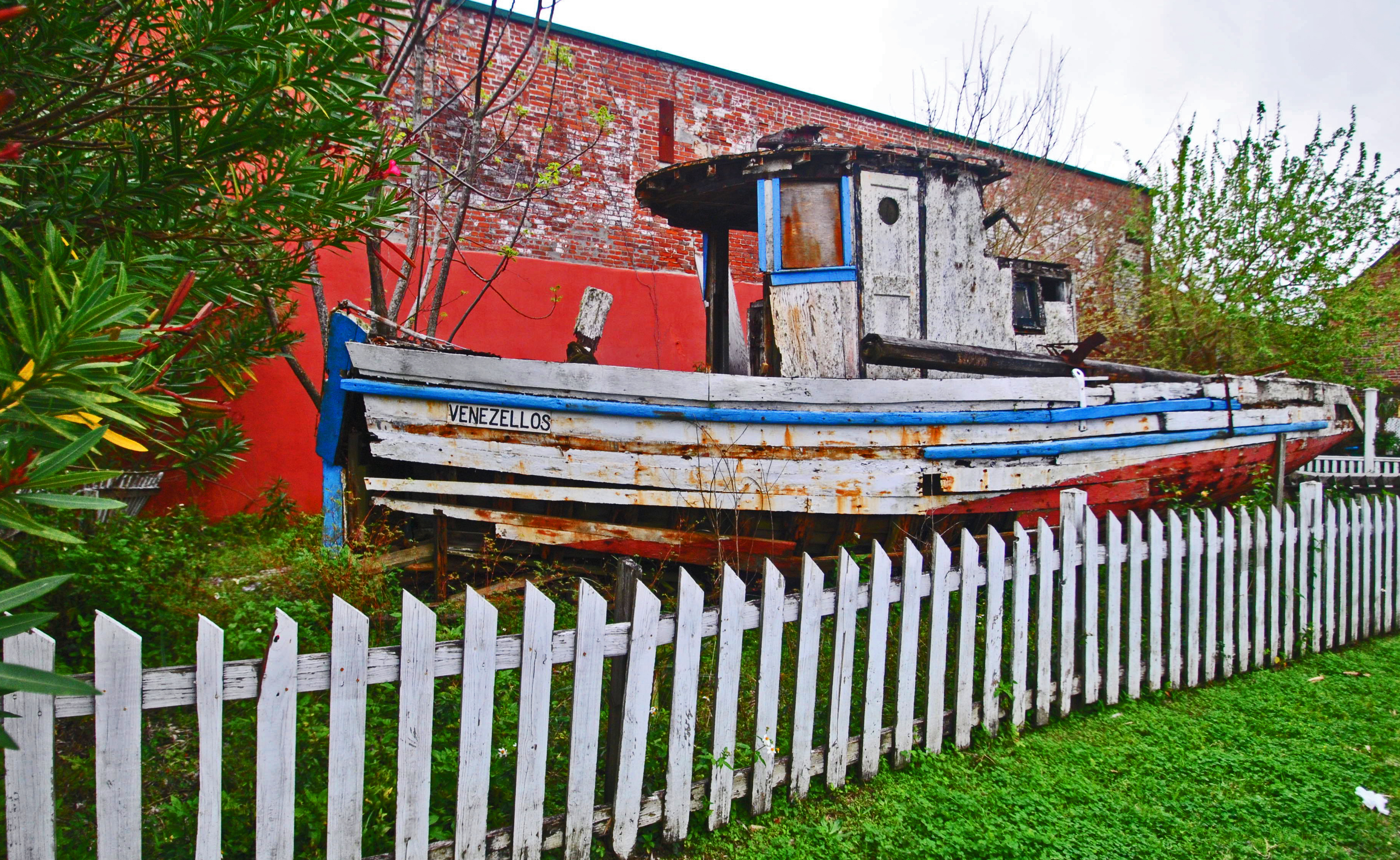 Old boat in Apalachicola, Florida, with old fence hemming it in.